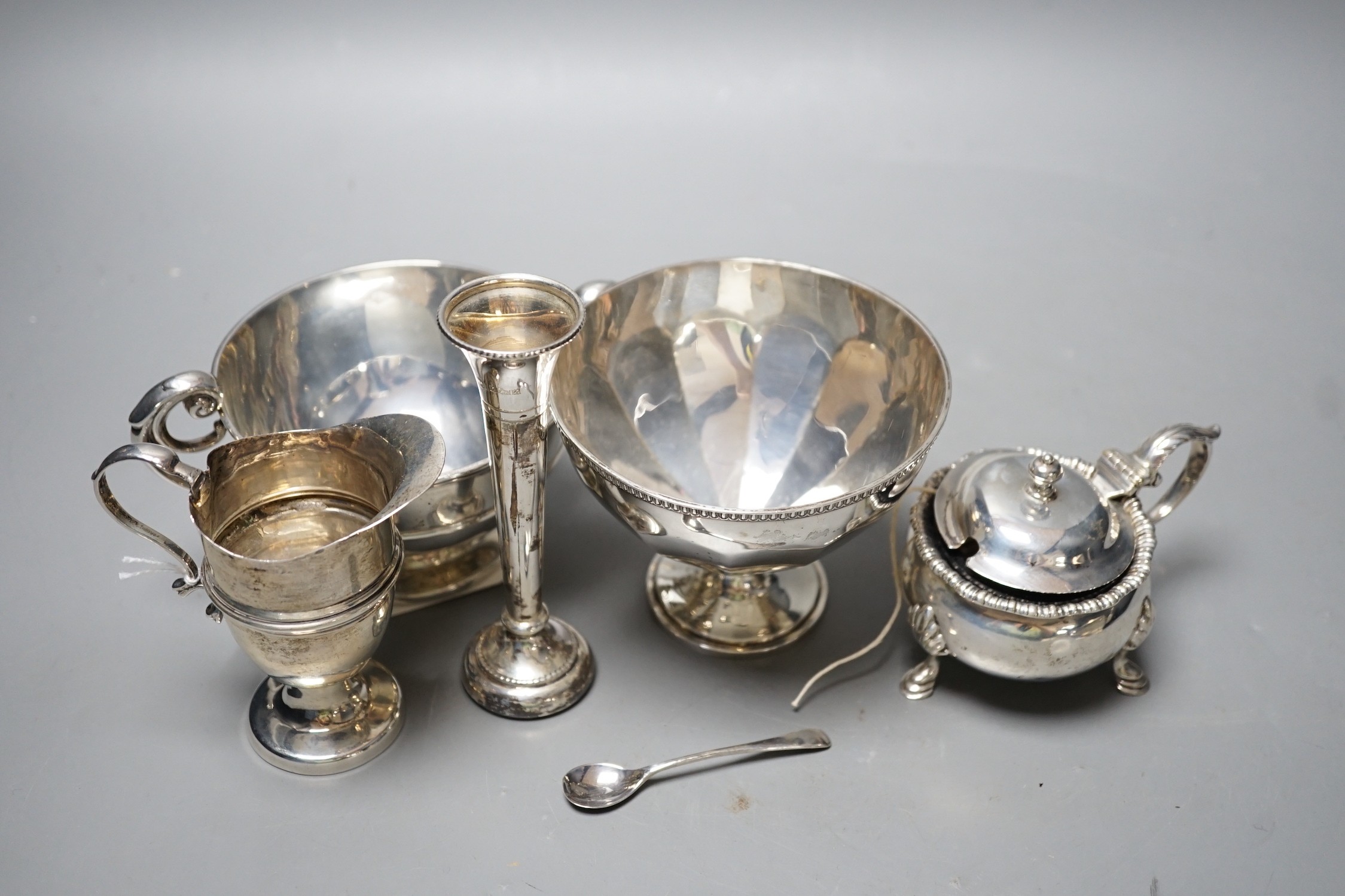 A late Victorian silver helmet shaped cream jug, a silver sugar bowl, a silver mustard pot, a silver mounted posy vase and a silver two handled bowl.